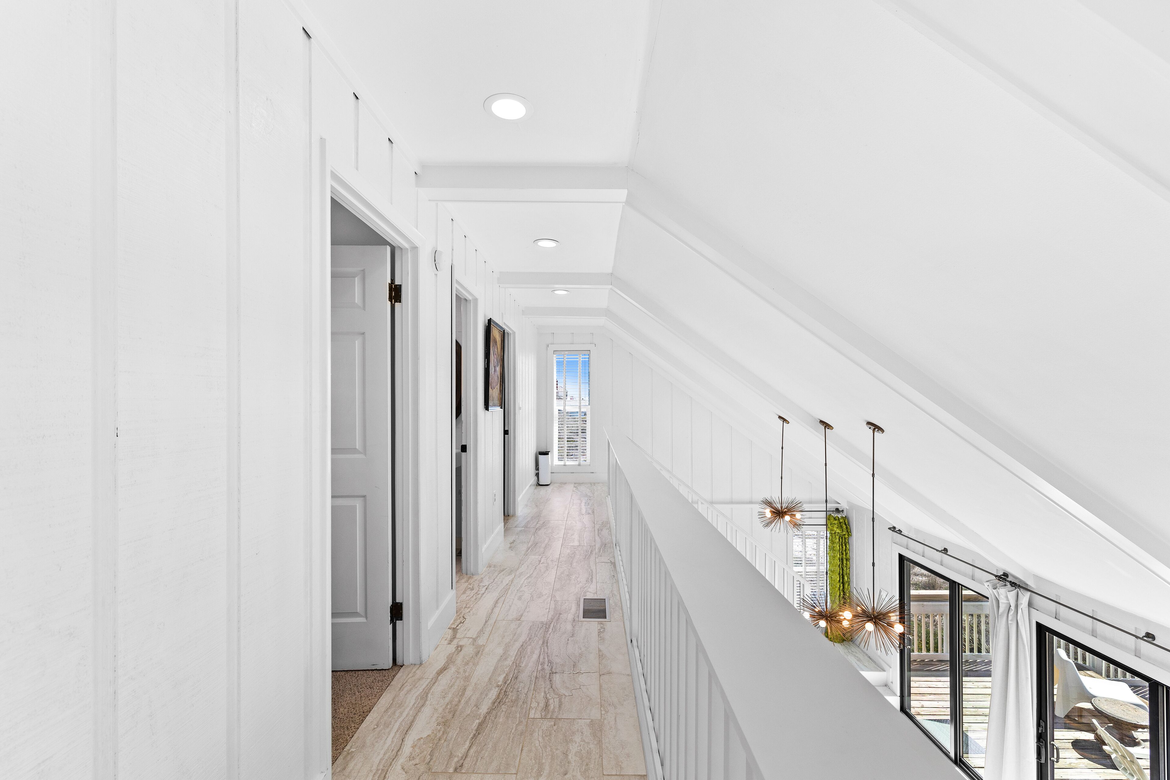 A modern interior with a long hallway, white walls, and a high ceiling.