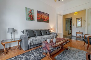 A living room with a sofa, a coffee table, a lamp, and two paintings on the wall.