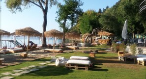 A beachside lounge area with thatched umbrellas, lounge chairs, and a view of the sea.