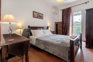 A bedroom with a bed, bedside tables, a lamp, a wooden cabinet, and a window with curtains.