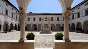 A courtyard with arches, a central fountain, and potted plants.
