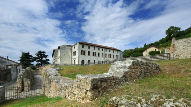 A historic building with a courtyard, stone walls, and a fenced area.