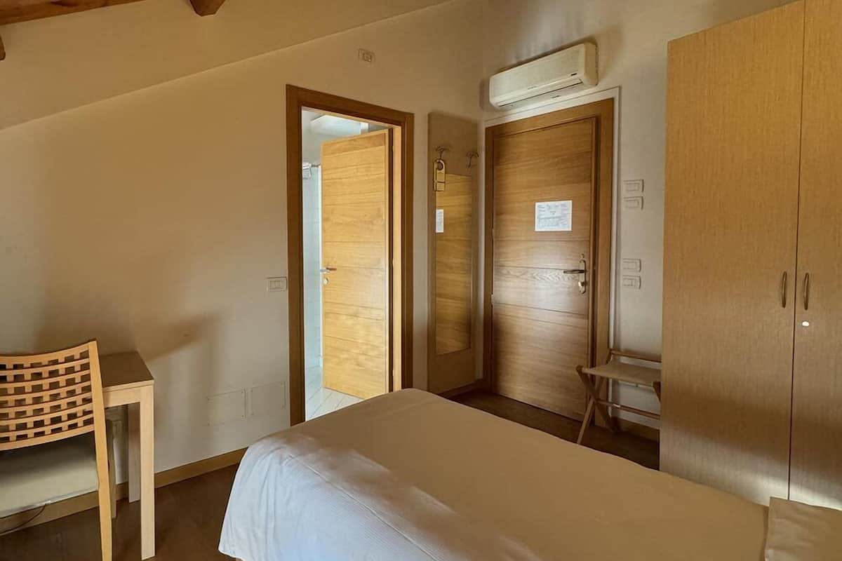 A bedroom with a bed, a desk, and a wardrobe.