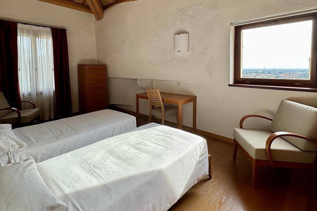 A room with two beds, a desk, a chair, and a window with a view.