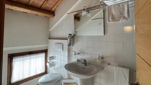 A bathroom with a toilet, sink, and window.