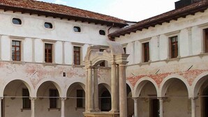 A courtyard with a central fountain, surrounded by a building with arched windows and a tiled roof.