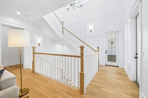 A spacious interior with a wooden staircase, a floor lamp, and a door leading to a balcony. - 30A White Dunes Retreat-Luxury Compound, Large Private Pool and Outdoor Space (Santa Rosa Beach)