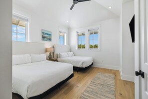 A bedroom with two beds, a ceiling fan, and a large window.