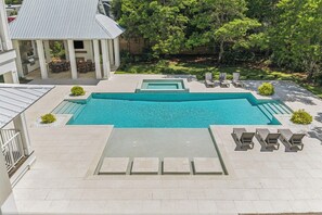 A swimming pool with a patio area, lounge chairs, and a gazebo.
