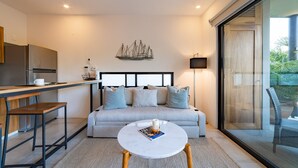 Un espace de vie moderne comprenant une cuisine, un canapé, une table basse et une grande fenêtre.