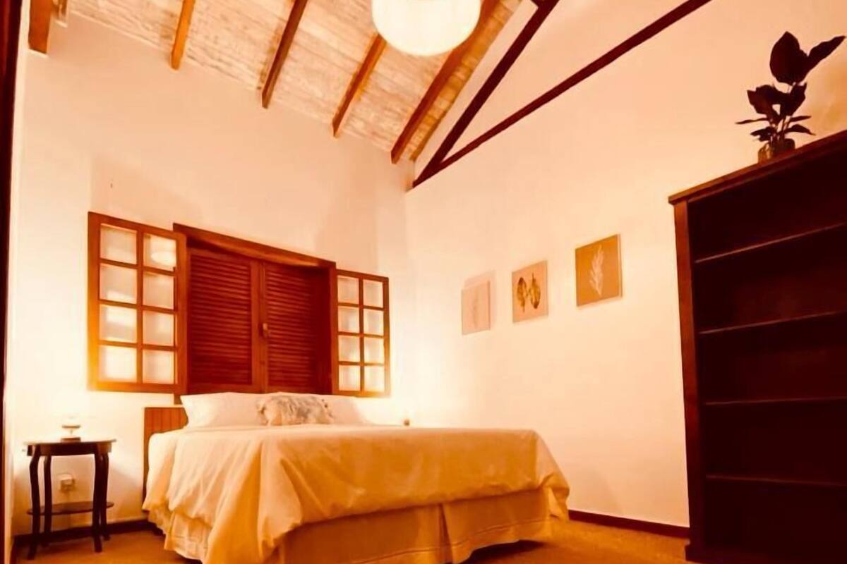 A room with a bed, a small table, a cabinet, and a ceiling light.