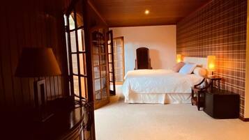 A bedroom with a large bed, a dresser, a nightstand, and a window with a view of the outside.