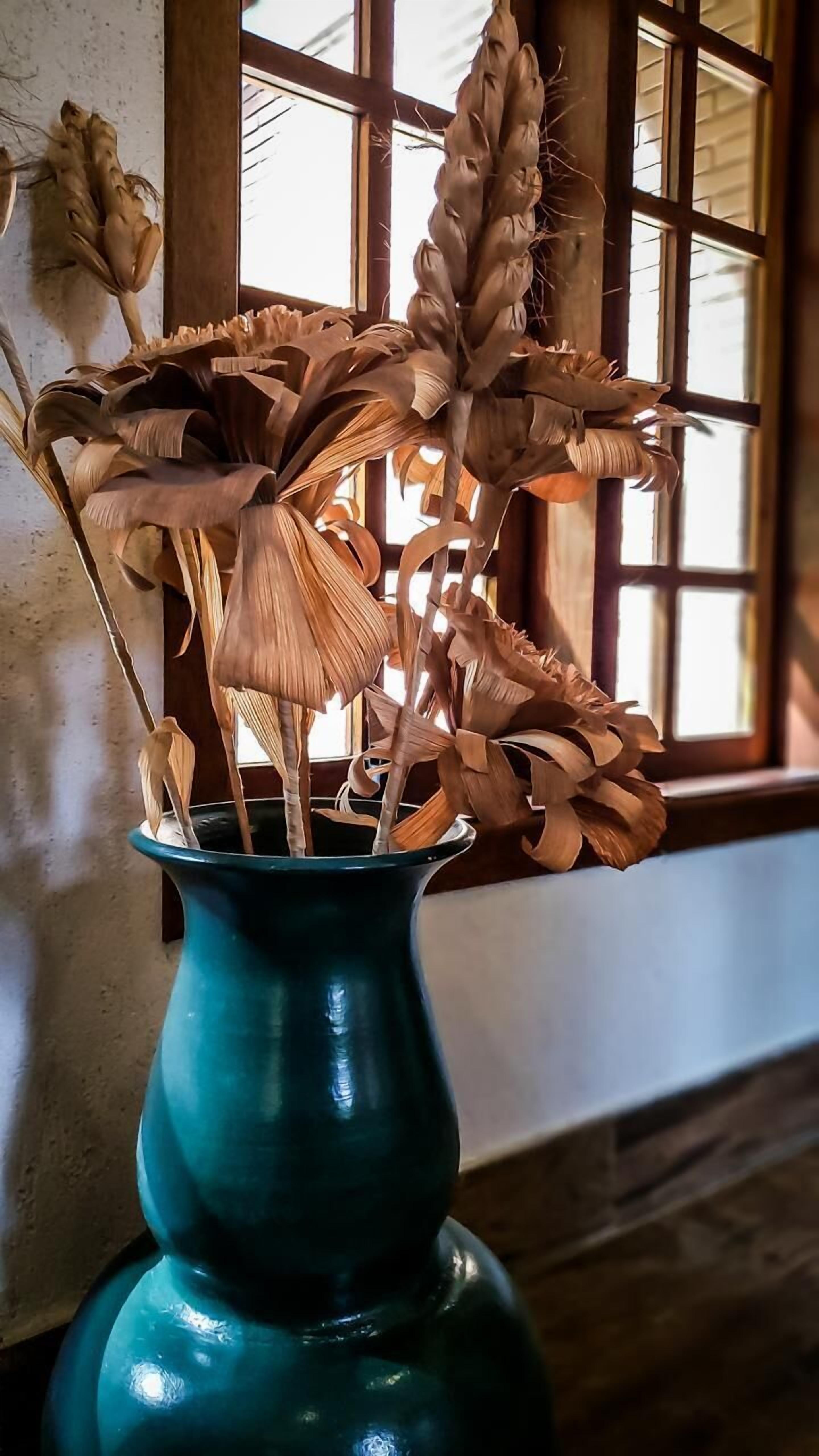 A vase with dried wheat stalks and corn husks.