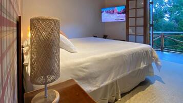 Quarto com cama, luminária, televisão e vista para o exterior.