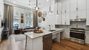 Une cuisine moderne avec des meubles blancs, un îlot central doté d’un évier et des appareils électroménagers en acier inoxydable.