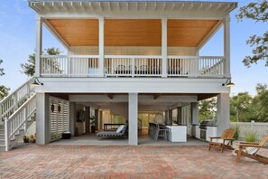 Une maison à deux étages dotée d’un patio couvert, d’une cuisine extérieure et d’un espace détente.