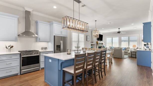 A modern kitchen with stainless steel appliances, a central island with bar stools, and pendant lighting. - Brand New Home, Sleeps 10, Pool and Screened-in Porch with TV! (St Simons Island)