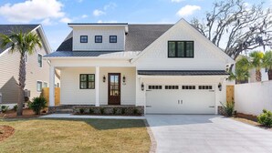 A two-story house with a garage, a front porch, and a well-maintained lawn. - Brand New Home, Sleeps 10, Pool and Screened-in Porch with TV! (St Simons Island)