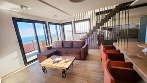 A modern living room with a sectional sofa, a wooden coffee table, and a staircase with a railing.