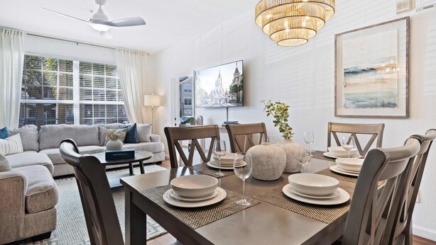 Un salon moderne avec un coin repas, comprenant un canapé, des fauteuils, une table à manger pour quatre personnes et un lustre.