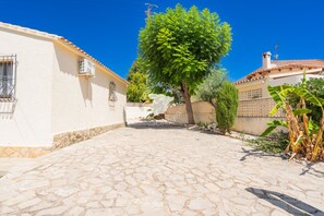 A cobblestone courtyard with a tree, a white building, and a fence. - CostaBlancaDreams - Casa Colibri in Calpe (Calpe)