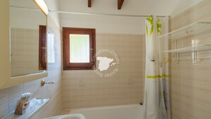 Une salle de bain avec une baignoire, une fenêtre et un rideau de douche.