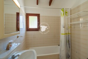 Un baño con bañera, ventana y cortina de ducha.