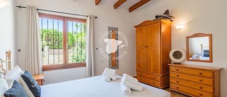 Een slaapkamer met een bed, een houten kledingkast en een raam met gordijnen.