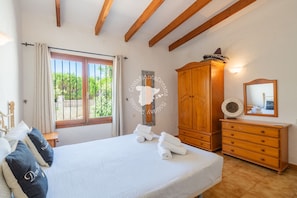 Un dormitorio con cama, armario de madera y ventana con cortinas.