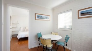 A room with a bed, a round table with chairs, and two framed pictures on the walls. - Vitamin Sea is pet friendly (Mollymook)