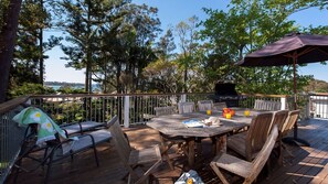 An outdoor deck with a wooden table and chairs, a grill, and a view of the ocean. - Vitamin Sea is pet friendly (Mollymook)