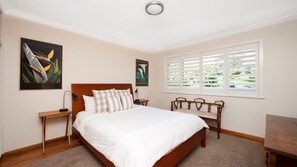 A bedroom with a bed, bedside tables, a nightstand, a window with blinds, and two wall-mounted pictures. - Vitamin Sea is pet friendly (Mollymook)