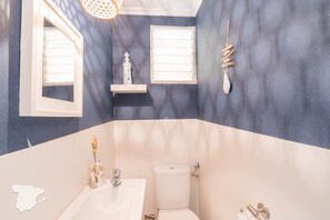 A bathroom with a white sink, a toilet, and a window with blinds.