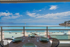 A table set for dining with a view of a beach and the sea.