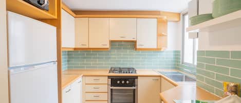 A compact kitchen with a refrigerator, stove, oven, and a sink.