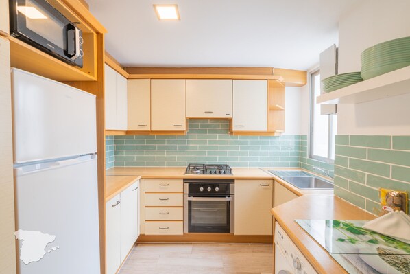 Una cocina compacta equipada con refrigerador, estufa, horno y pileta.