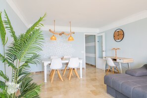 A dining area with a table and chairs, a plant, and a wall clock.