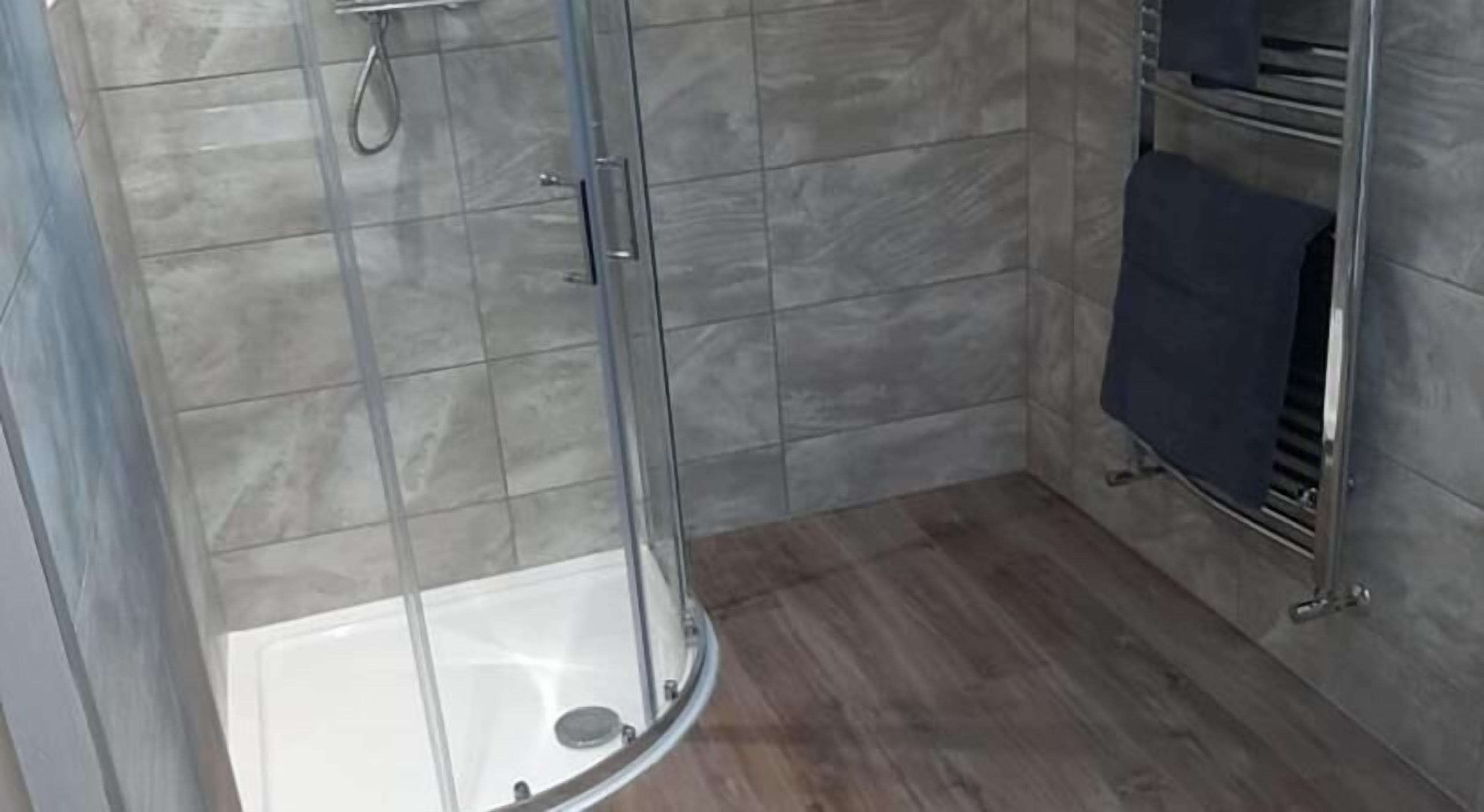 Une salle de bain moderne avec une douche à parois de verre, une baignoire blanche et un porte-serviettes avec une serviette.