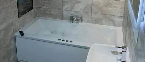 A bathroom with a bathtub, a sink, and a shower.