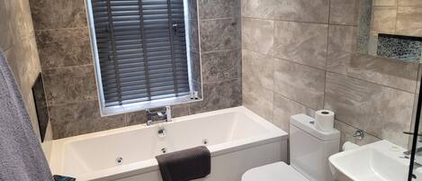 A modern bathroom with a bathtub, toilet, and sink.