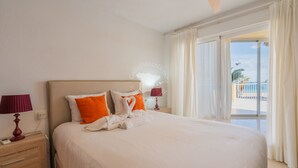 A hotel room with a large bed, two bedside lamps, a nightstand, and a view of the beach. - CostaBlancaDreams - Apartment Gran Sol in Calpe (Calpe / Calp)