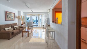 A living room with a sofa, a coffee table, and a TV. There is a door leading to a balcony. - CostaBlancaDreams - Apartment Gran Sol in Calpe (Calpe / Calp)