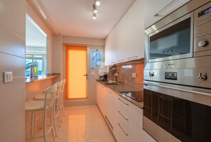 Une cuisine moderne dotée d’un four encastré, d’un plan de travail avec un évier et d’un coin bar avec des tabourets.