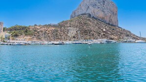 A marina with boats docked, a large rock formation in the background, and buildings on the hillside. - CostaBlancaDreams - Apartment Gran Sol in Calpe (Calpe / Calp)