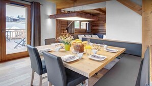 Een eetgedeelte met een houten tafel, zwarte stoelen en een bank.
