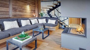 Een moderne woonkamer met een grijze modulaire bank, een salontafel en een open haard.