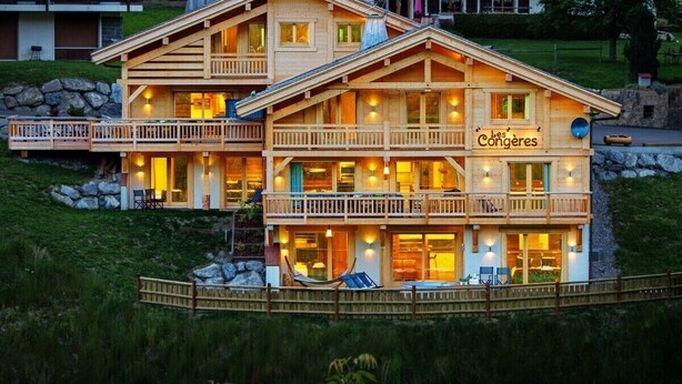 Een houten chalet met meerdere balkons en een bord waarop 'Les Congères' staat.