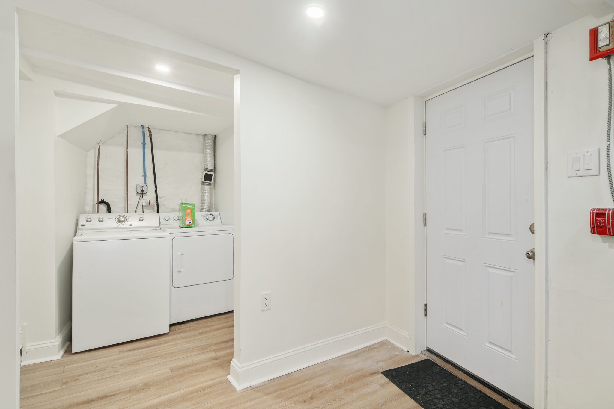 A laundry room with a washer and dryer, a water heater, and a fire alarm.