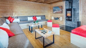 Ein modernes Wohnzimmer mit Kamin, Holzwänden und einer Sofagarnitur.