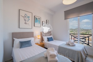 A hotel room with two beds, a view of the city, and artwork on the wall.